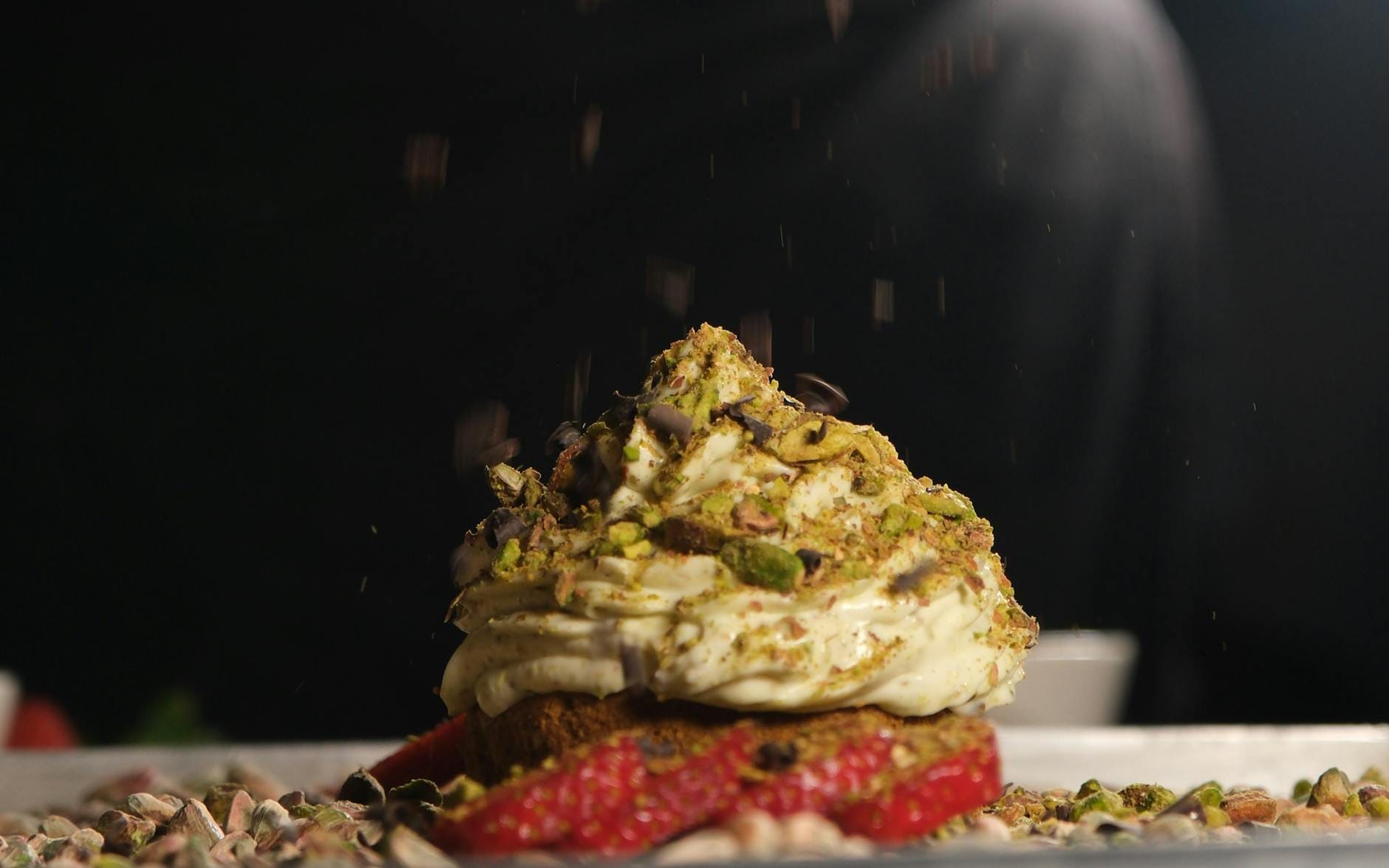 Deser z kremem pistacjowym i truskawkami podany w eleganckim pucharku