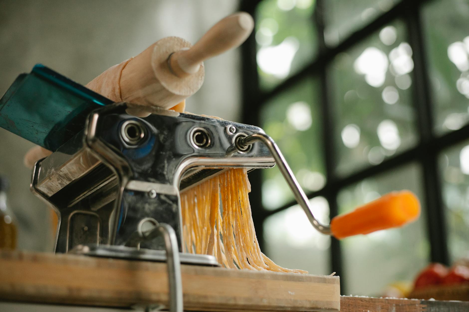 Mała kuchnia, wielka Italia: jak gotować włosko, gdy nie masz czasu ani sprzętu Maszynka do makaronu z surowym ciastem na drewnianym blacie w kuchni