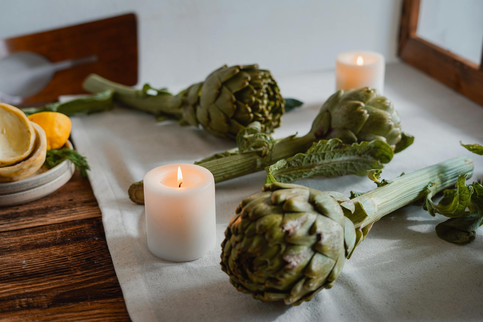 Karczochy, cytryny i zapalone świece na rustykalnym stole