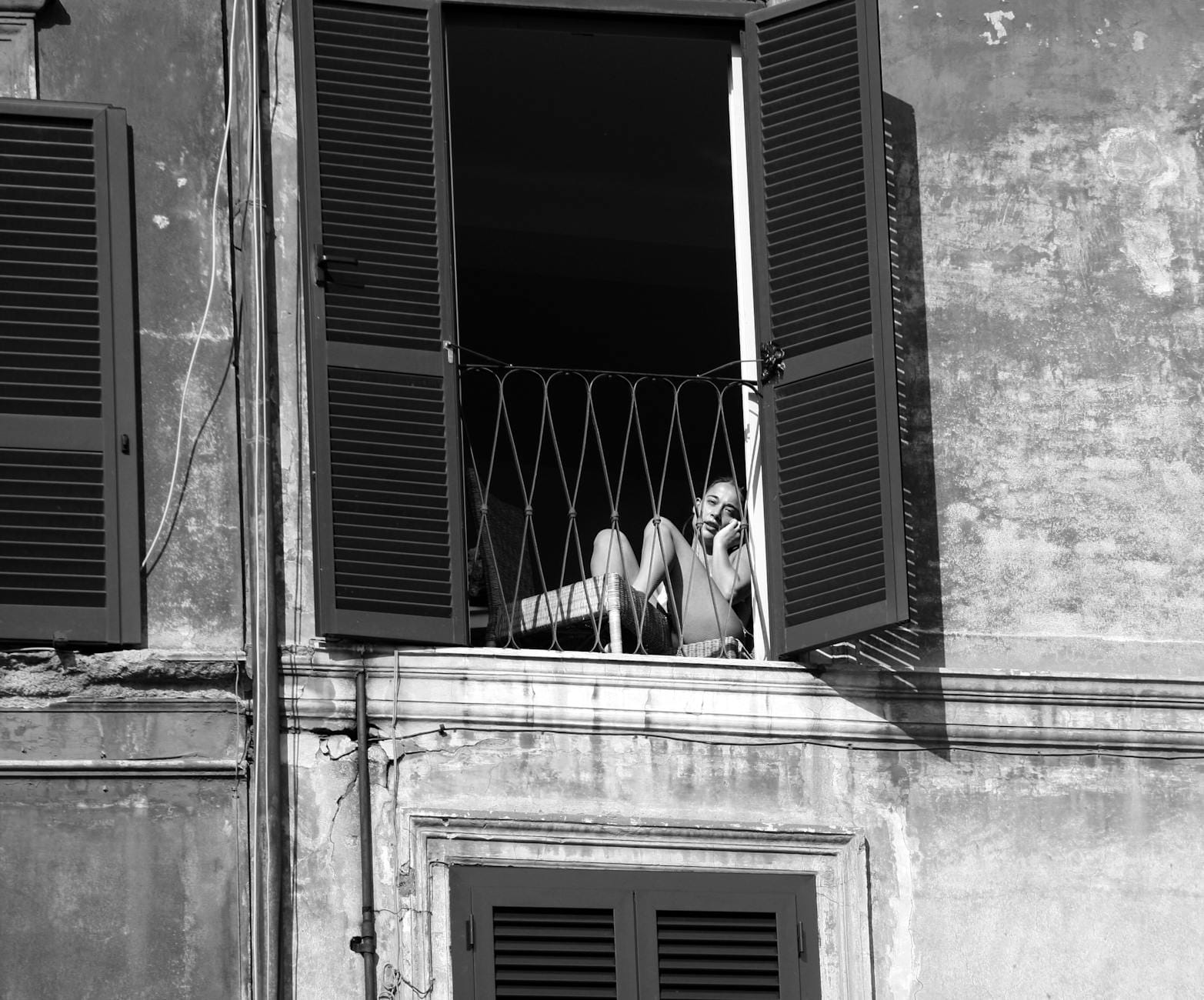 Czarno-białe ujęcie osoby siedzącej przy oknie w Rzymie