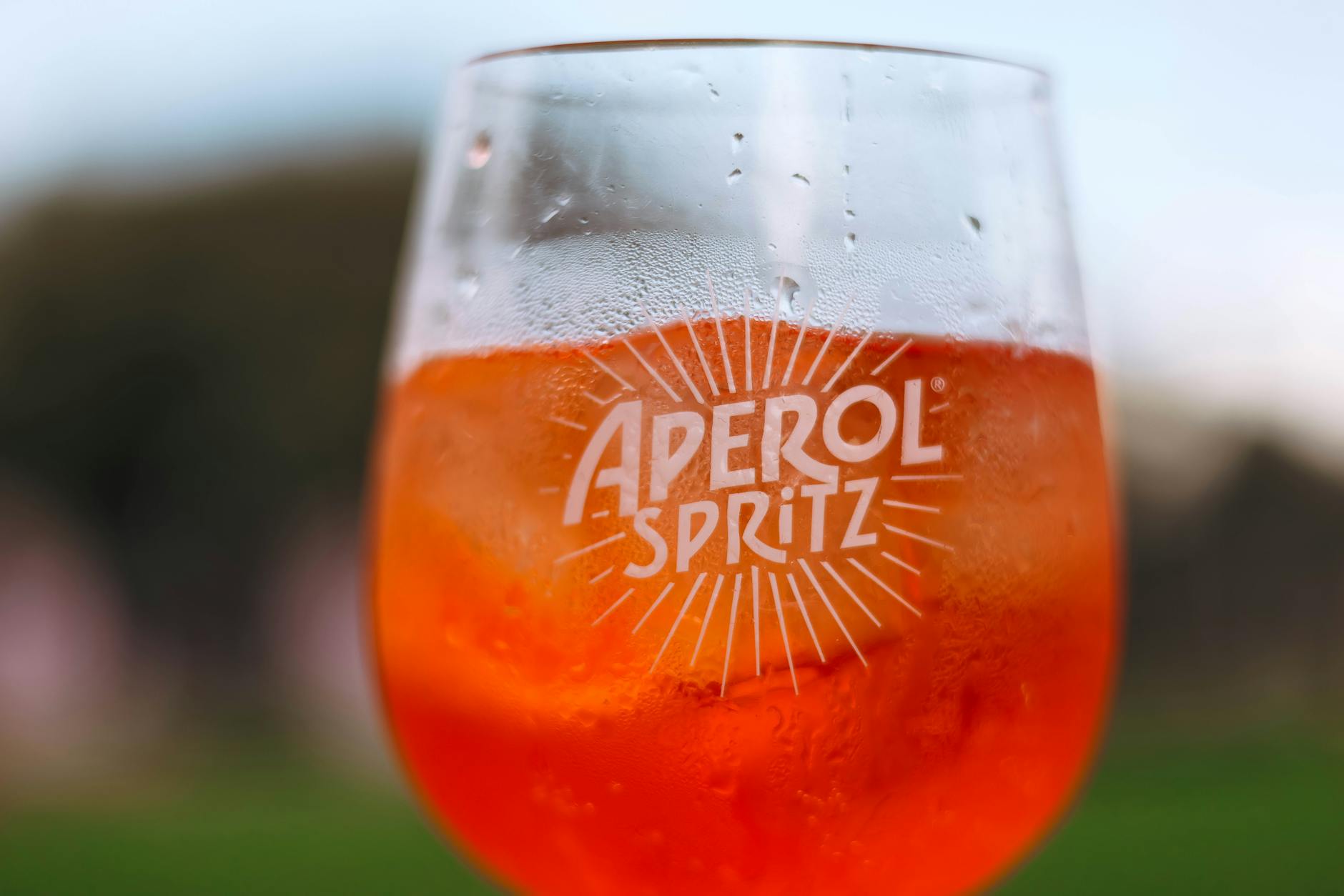 Kieliszek Aperol Spritz na słońcu z rozmytym plenerem w tle