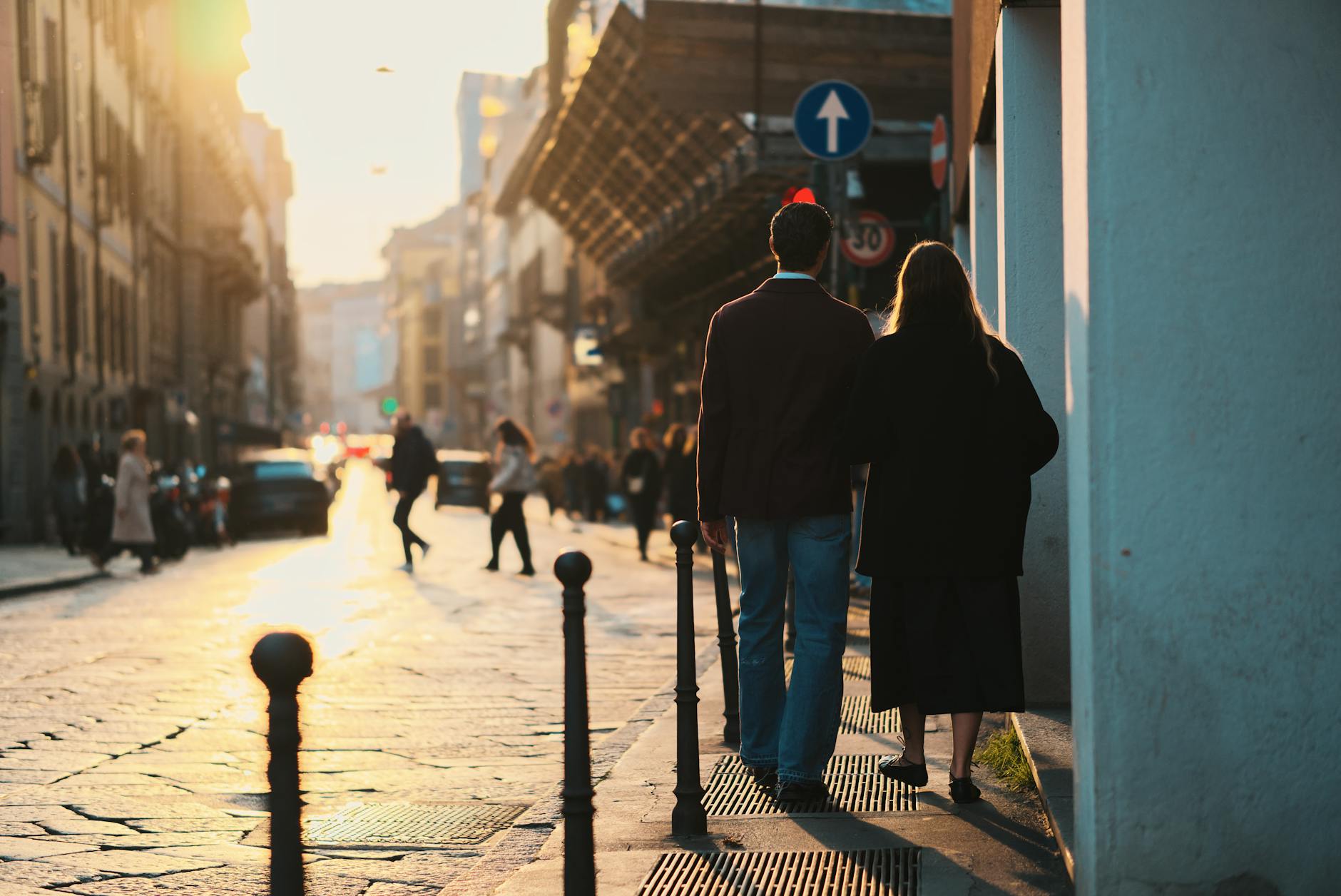 Para spaceruje objęta ulicą Mediolanu o zachodzie słońca