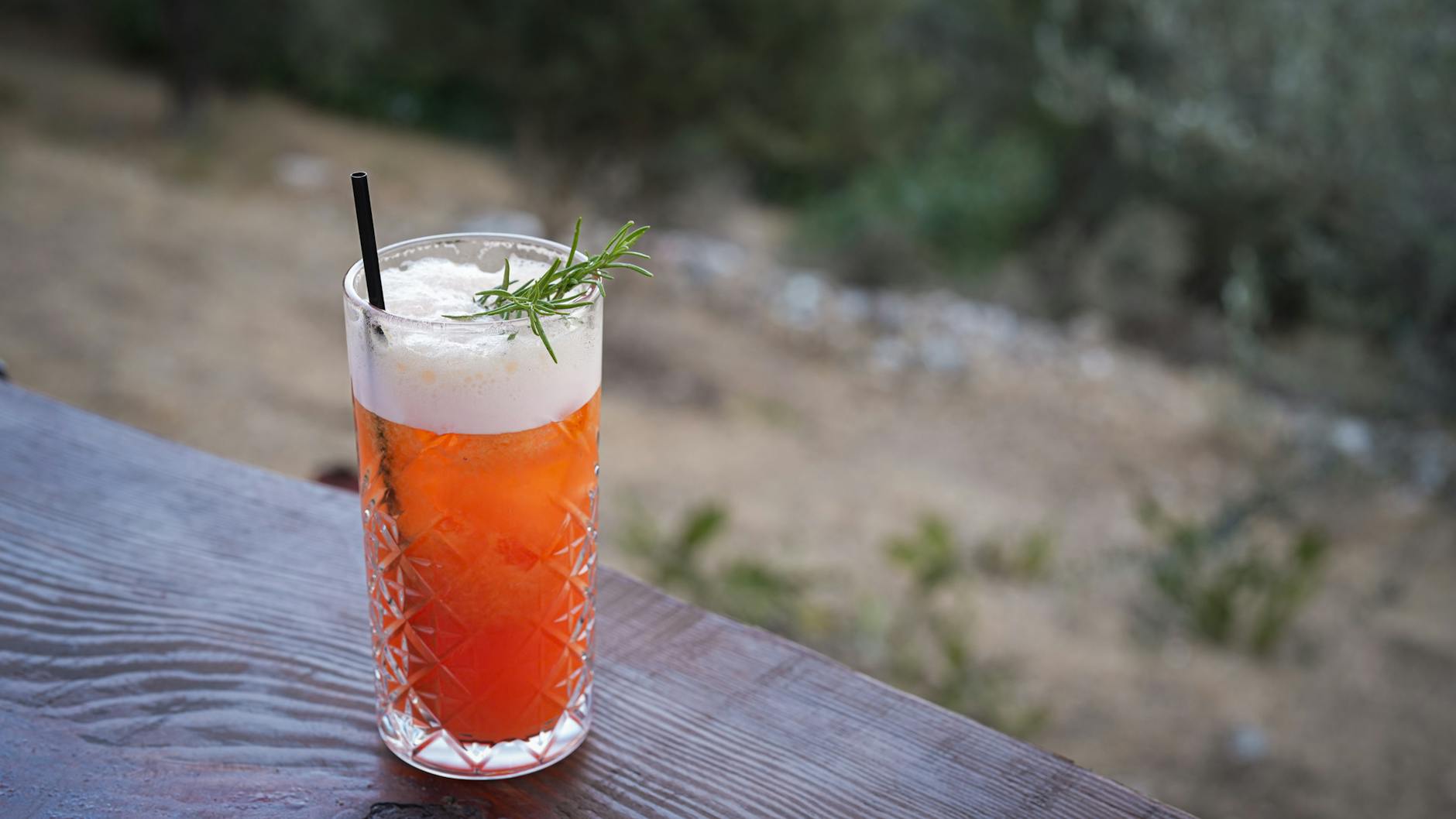 Aperol Spritz z rozmarynem w kryształowej szklance na zewnętrznym stoliku