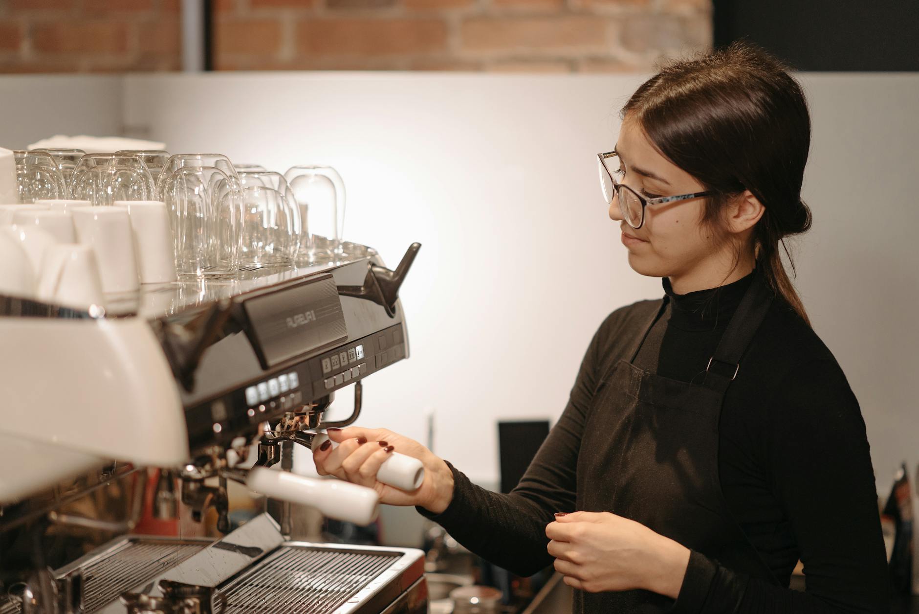 Barista przygotowuje kawę latte na profesjonalnym ekspresie w kawiarni