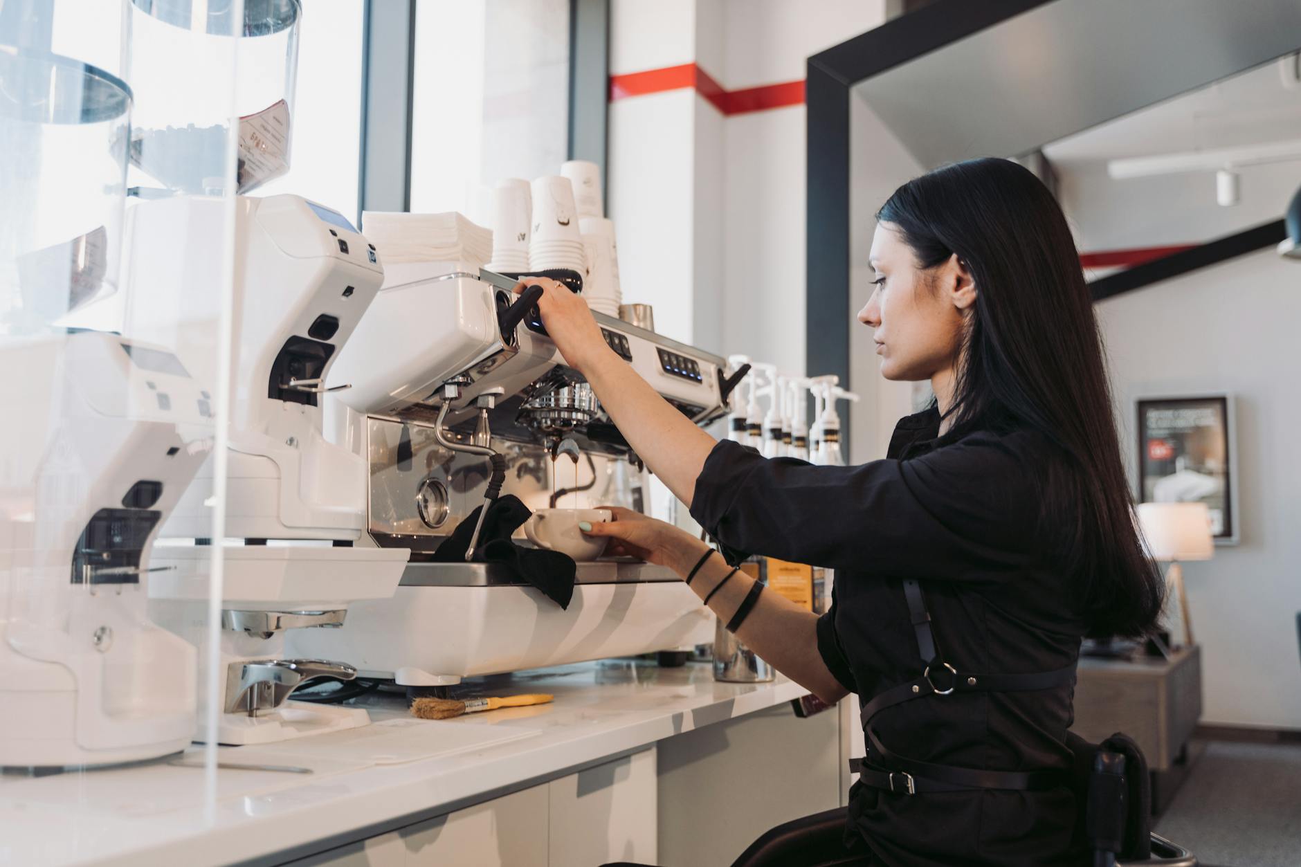 Barista przygotowuje latte przy nowoczesnym ekspresie w kawiarni