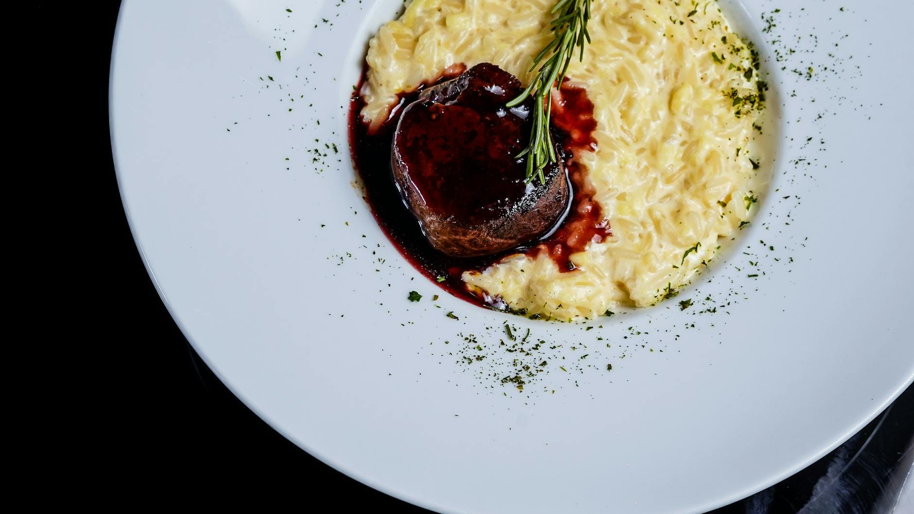 Wino do risotta: jak dobrać białe lub czerwone, żeby nie zdominować smaku Risotto z polędwicą wołową i sosem z czerwonego wina, udekorowane rozmarynem