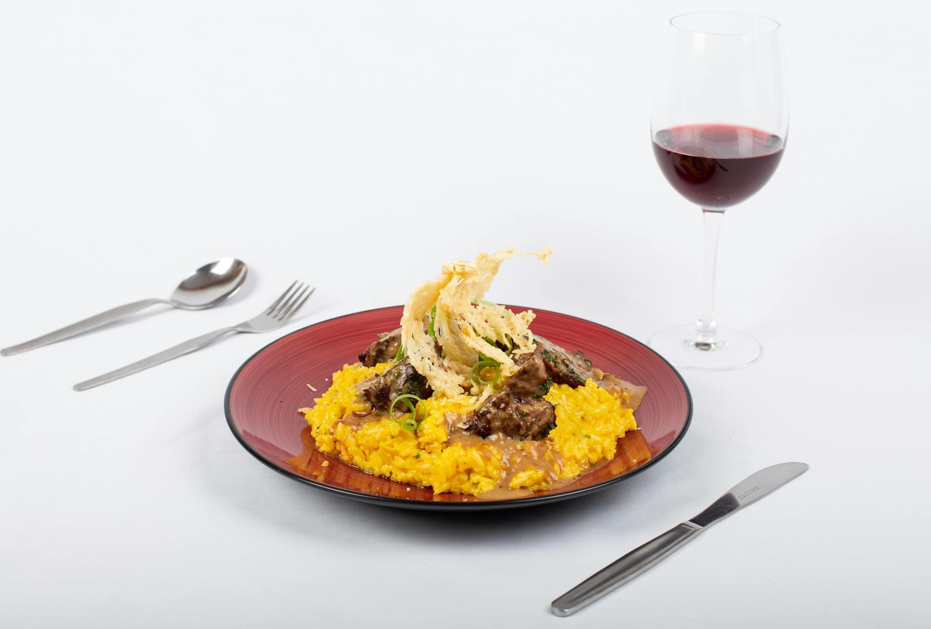 Risotto z żółtym ryżem podane w restauracji, obok kieliszek białego wina