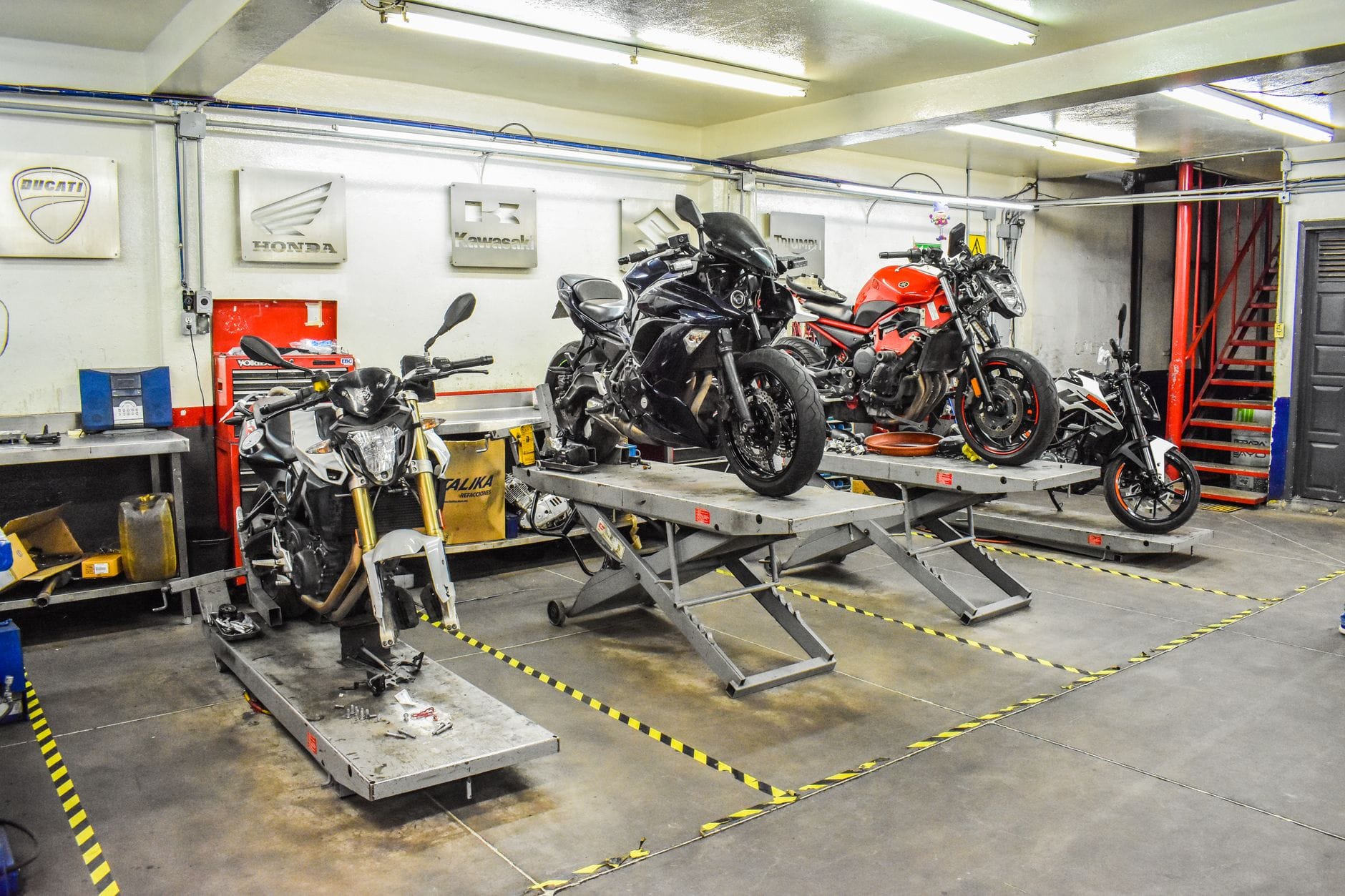 Jak przygotować motocykl do sezonu: praktyczny poradnik dla początkujących i zaawansowanych Warsztat motocyklowy z Ducati, Hondą i Kawasaki na podnośnikach