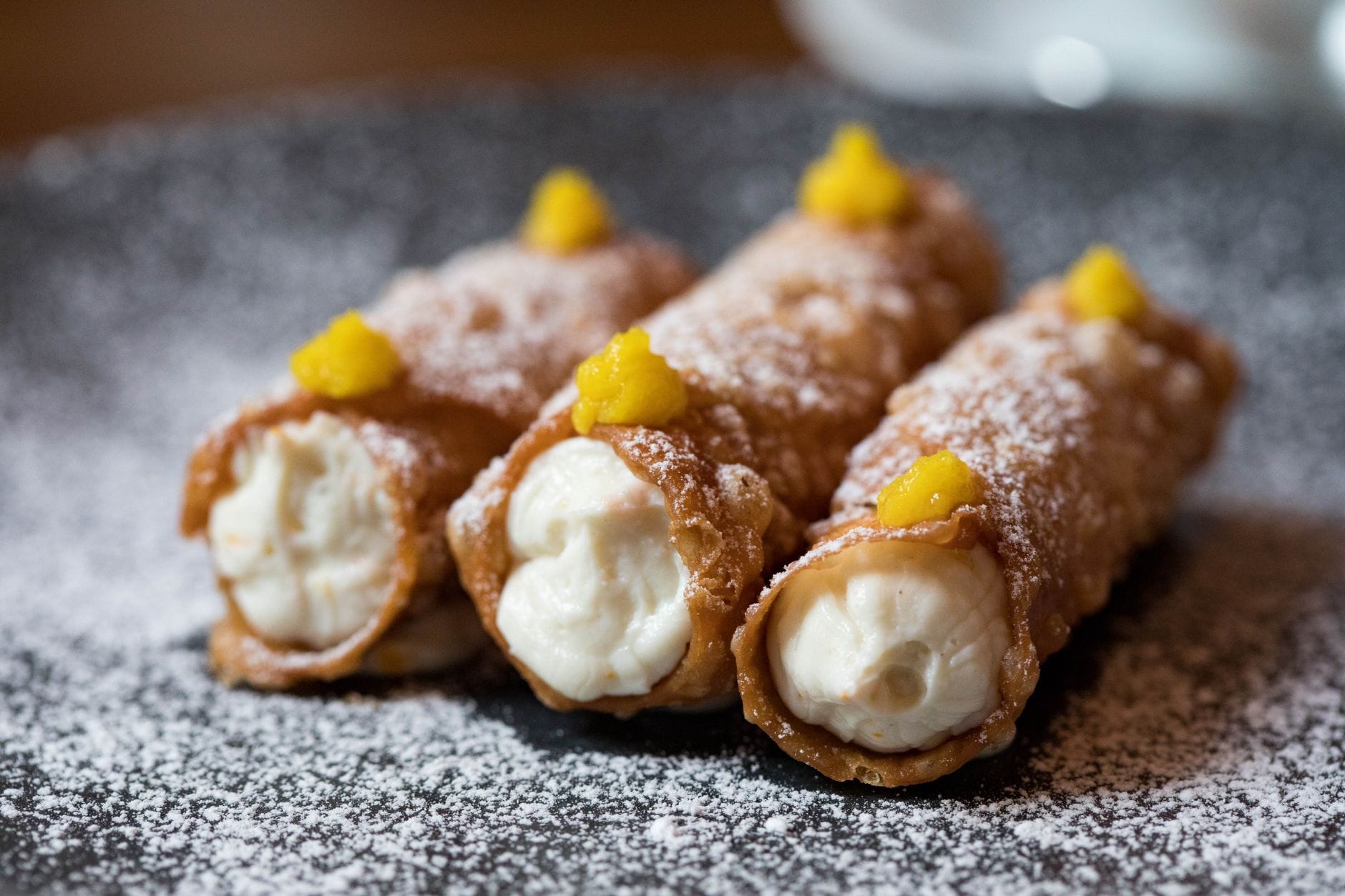 Ricotta w deserach: 7 pomysłów na lekkie słodkości w stylu włoskim Włoskie cannoli z kremowym nadzieniem posypane cukrem pudrem na talerzu