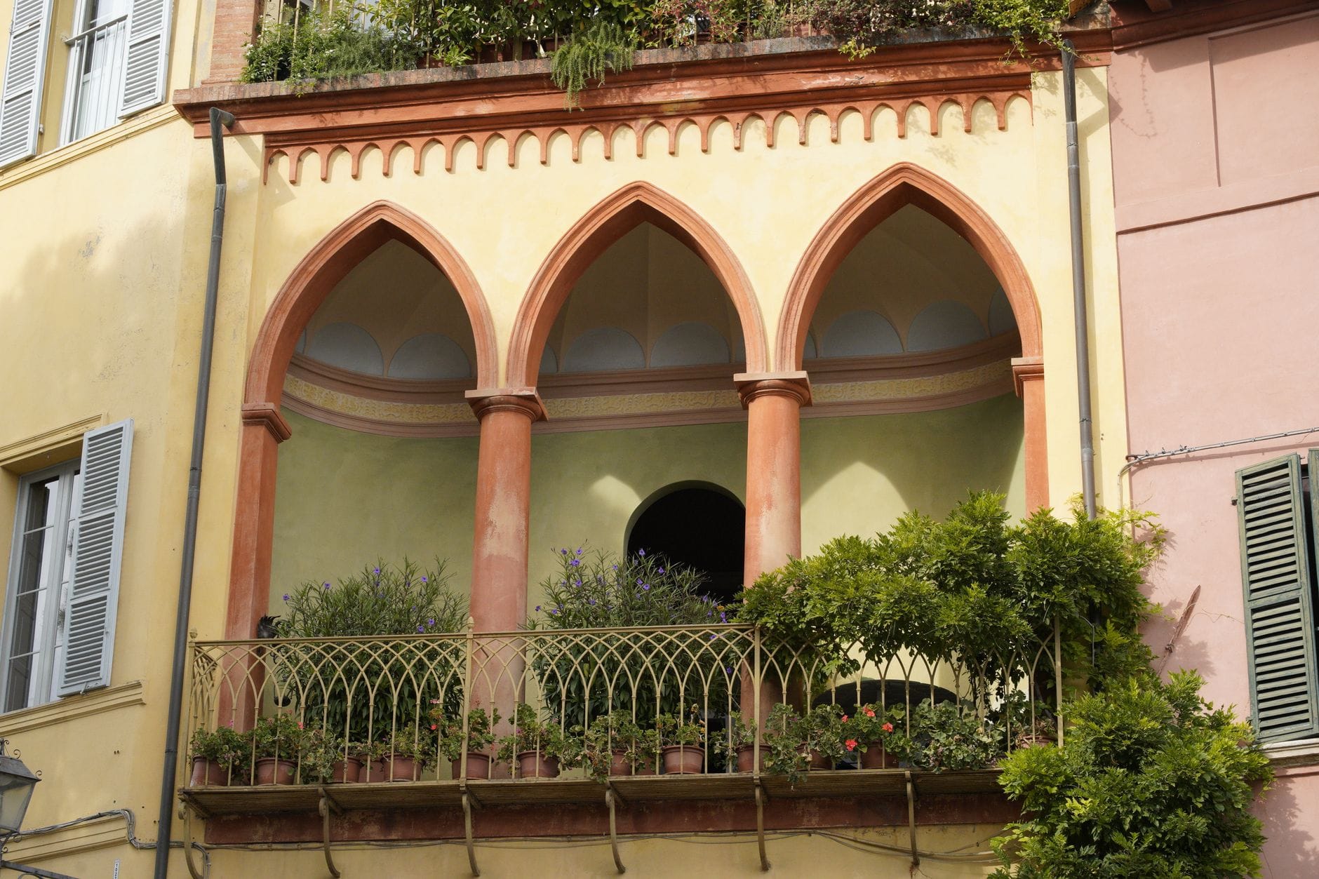 Elegancki włoski balkon z łukami i bujną roślinnością