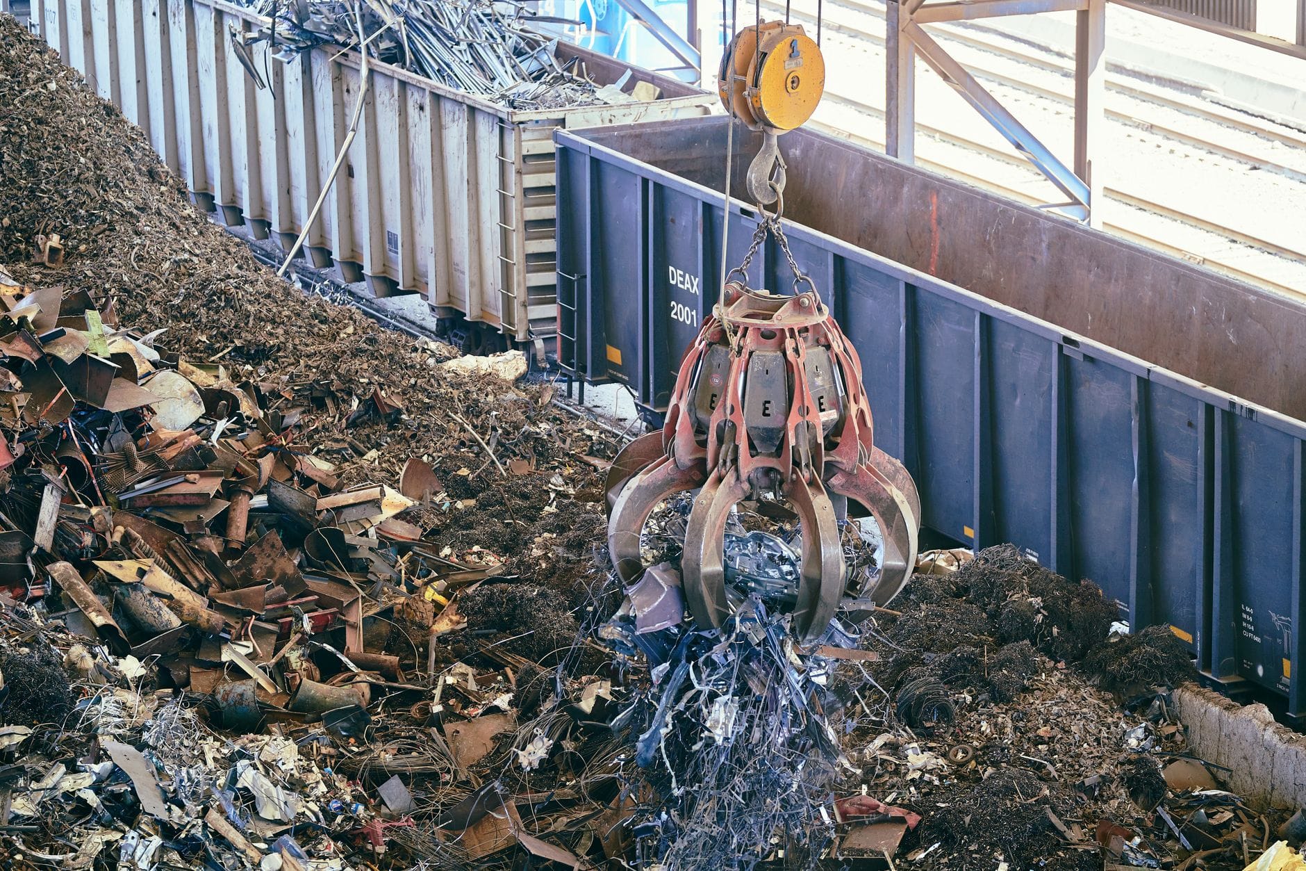 Chwytak dźwigu podnosi złom metalowy w zakładzie recyklingu