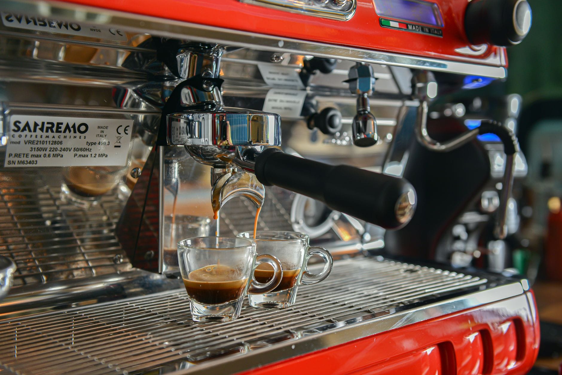 Zbliżenie na espresso nalewane do filiżanek z ekspresu Sanremo